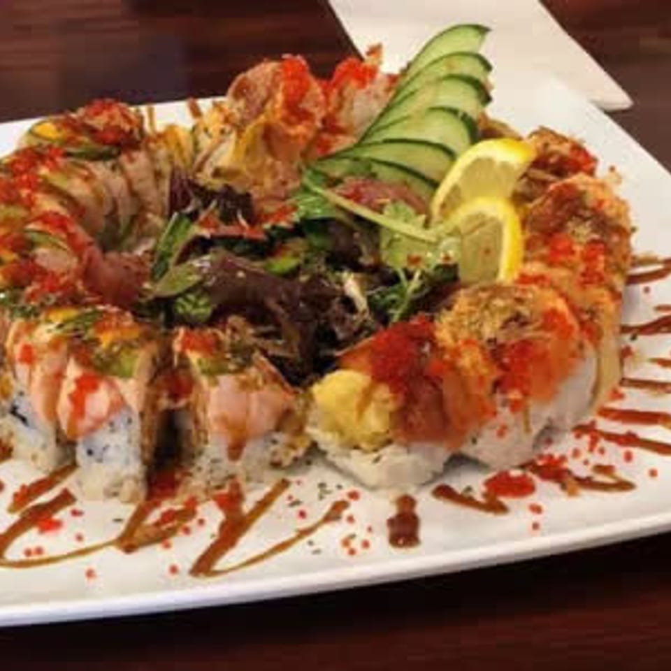 Sushi rolls arranged around greens on a square plate